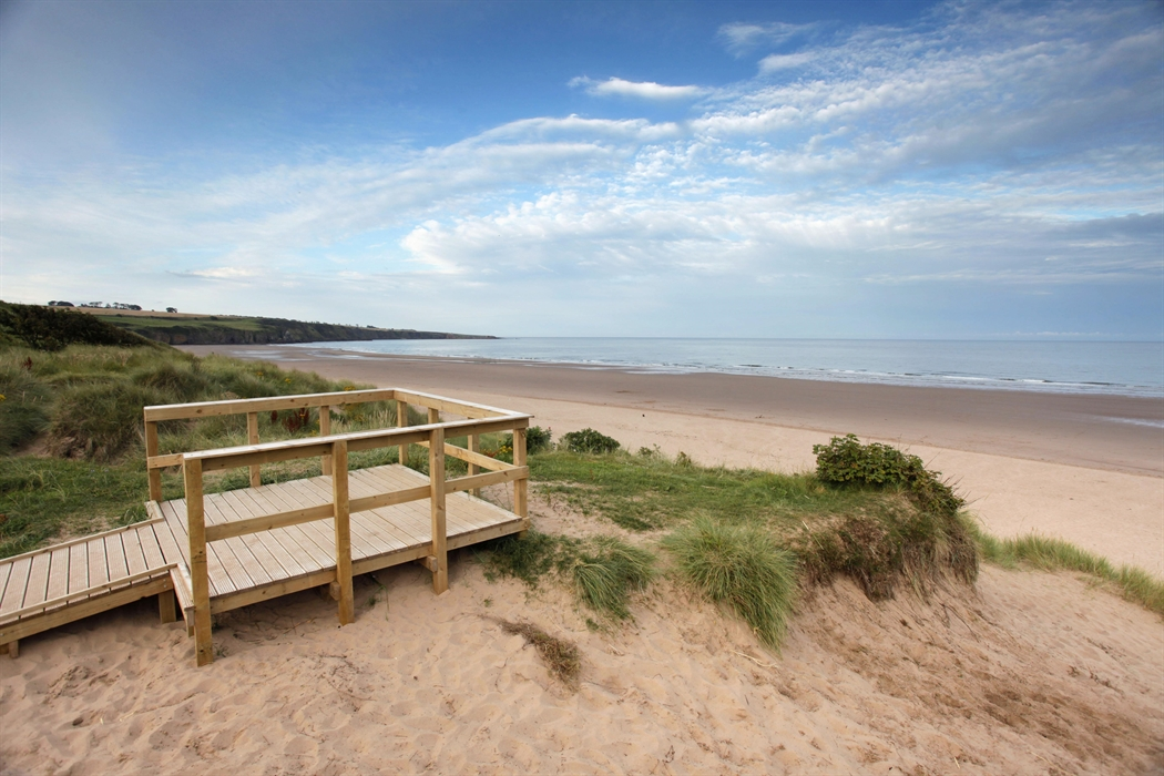Sandy beach and coastline with wooden viewing platform in foreground