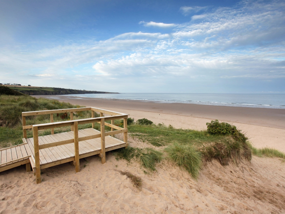 Sandy beach and coastline with wooden viewing platform in foreground