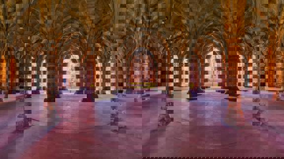Glasgow University Cloisters, a series of eerie gothic arches and pillars adorned with fairy lights, with the courtyard beyond