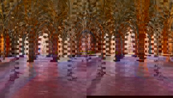 Glasgow University Cloisters, a series of eerie gothic arches and pillars adorned with fairy lights, with the courtyard beyond