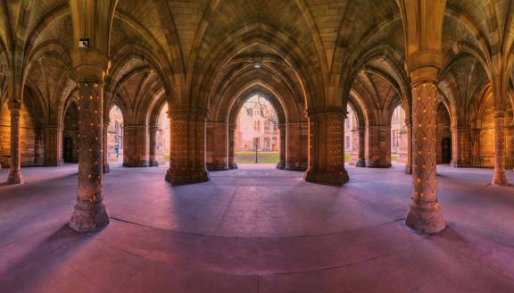 Glasgow University Cloisters, a series of eerie gothic arches and pillars adorned with fairy lights, with the courtyard beyond