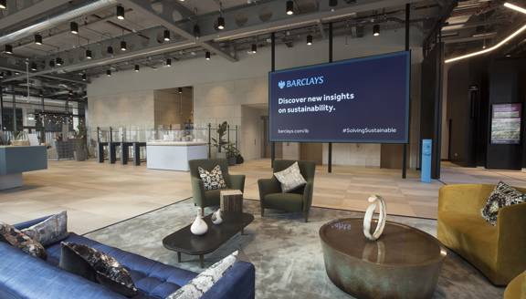 Interior view of Barclays campus in Glasgow with a soft seating aerea in the foreground and reception desk behind it.